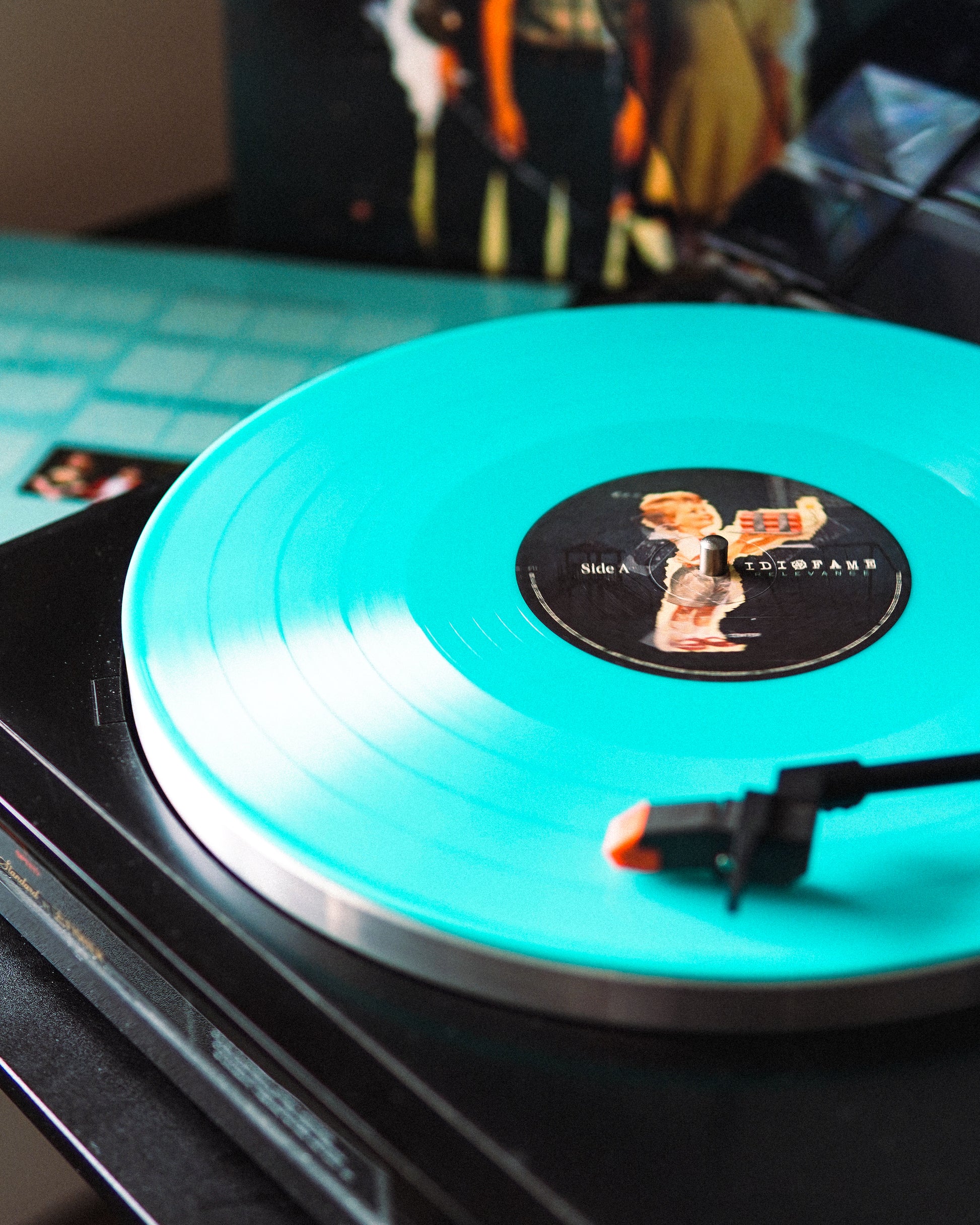 Turquoise vinyl record on a turntable with a visible label.